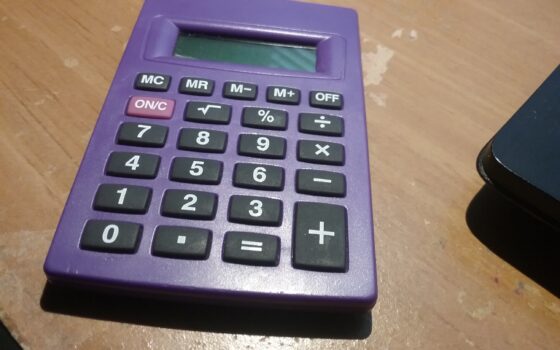 Calculadora de quatro funções sobre uma mesa, representando a conferência de dados financeiros do beneficiário do INSS