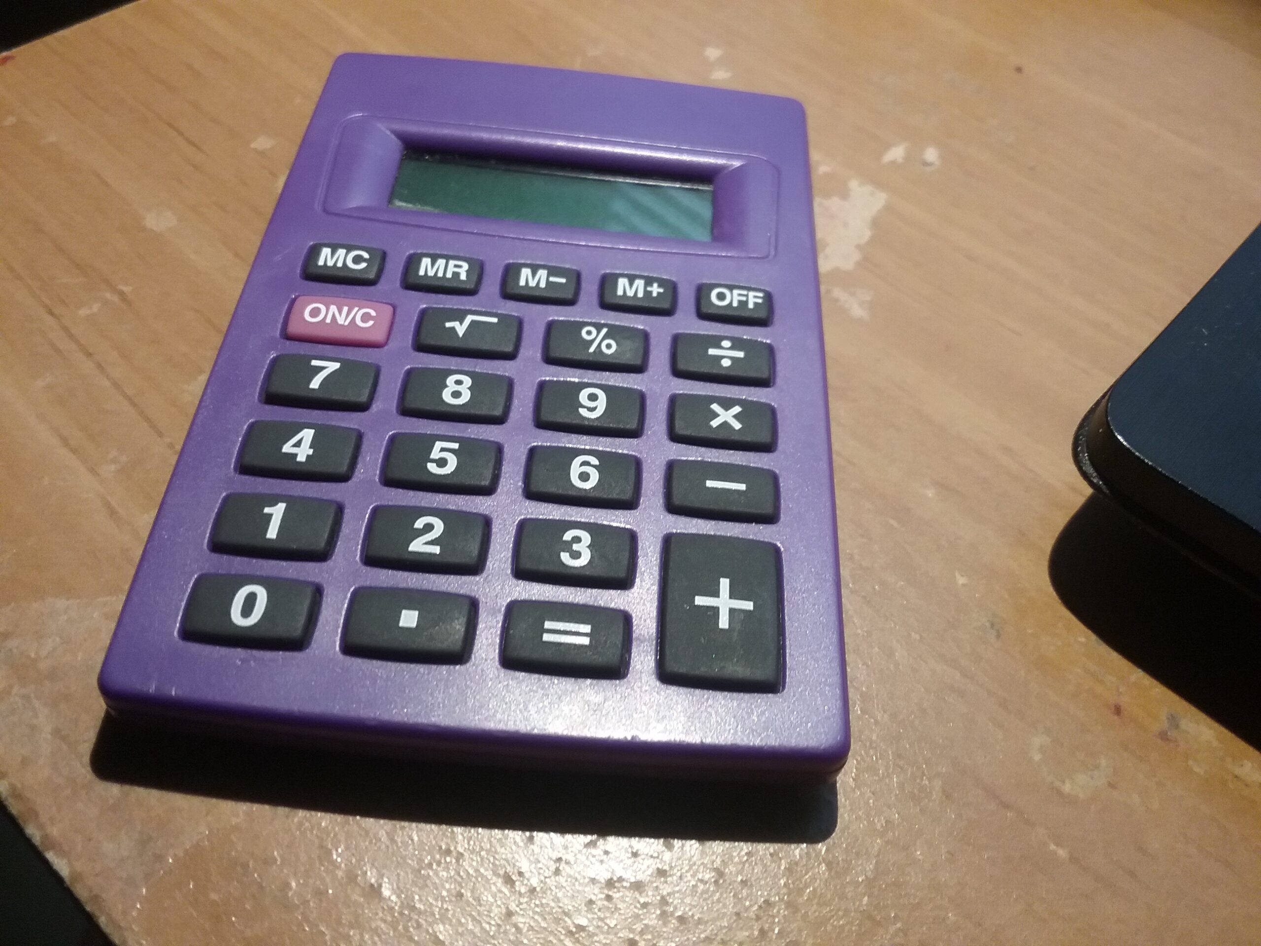 Calculadora de quatro funções sobre uma mesa, representando a conferência de dados financeiros do beneficiário do INSS