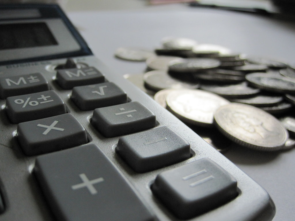 Calculadora ao lado de cédulas de dinheiro sobre uma superfície clara, em contexto de análise financeira