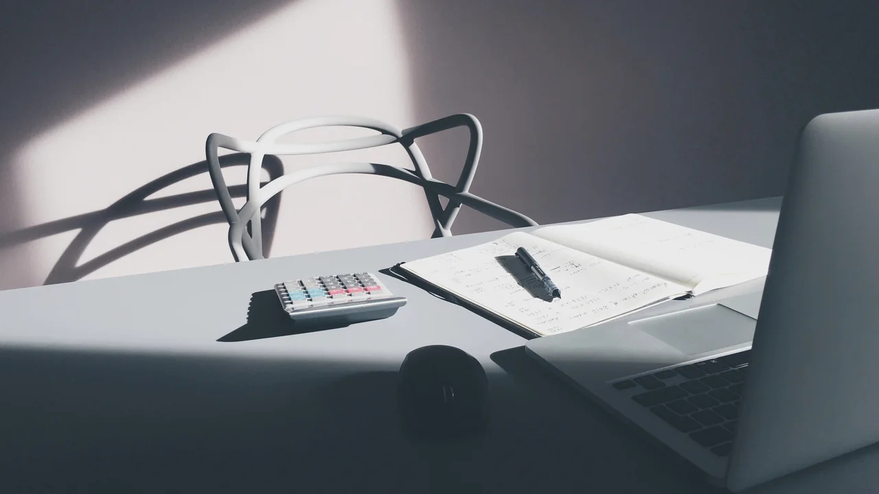 Calculadora ao lado de computador e documentos, usada para simular parcelas de uma dívida