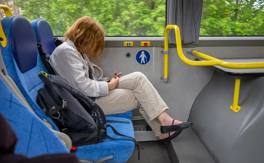Mulher consulta o celular sentada em um ônibus