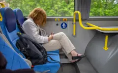 Mulher consulta o celular sentada em um ônibus