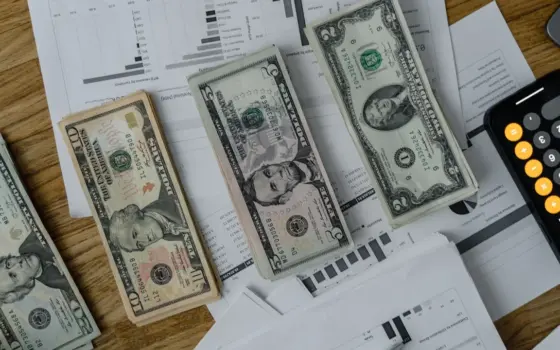Mesa de planejamento financeiro com dinheiro, documentos, calculadora e computador para um pequeno negócio