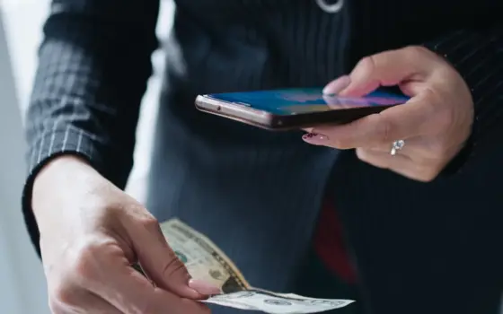 Pessoa segurando smartphone e dinheiro para fazer um pagamento digital