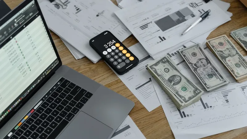 Notas, calculadora e documentos financeiros sobre uma mesa, representando a comparação de CDBs.