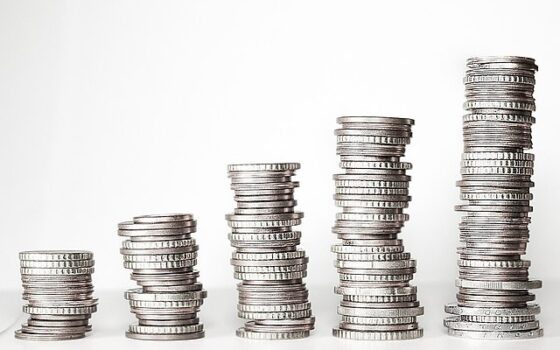 Gráfico de linhas e moedas sobre uma mesa, representando o acompanhamento de investimentos.