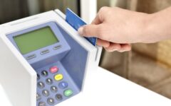 Mão inserindo um cartão de crédito em uma máquina de pagamento azul