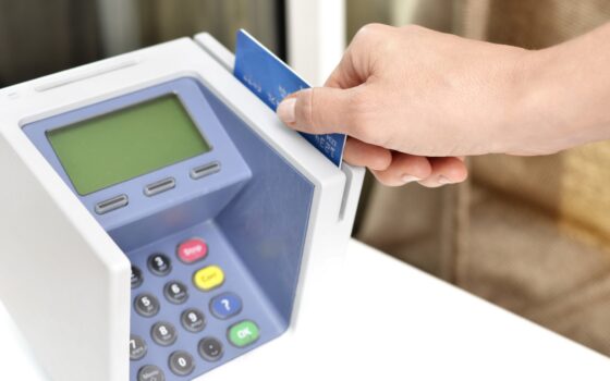 Mão inserindo um cartão de crédito em uma máquina de pagamento azul