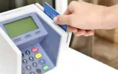 Mão inserindo um cartão de crédito em uma máquina de pagamento azul