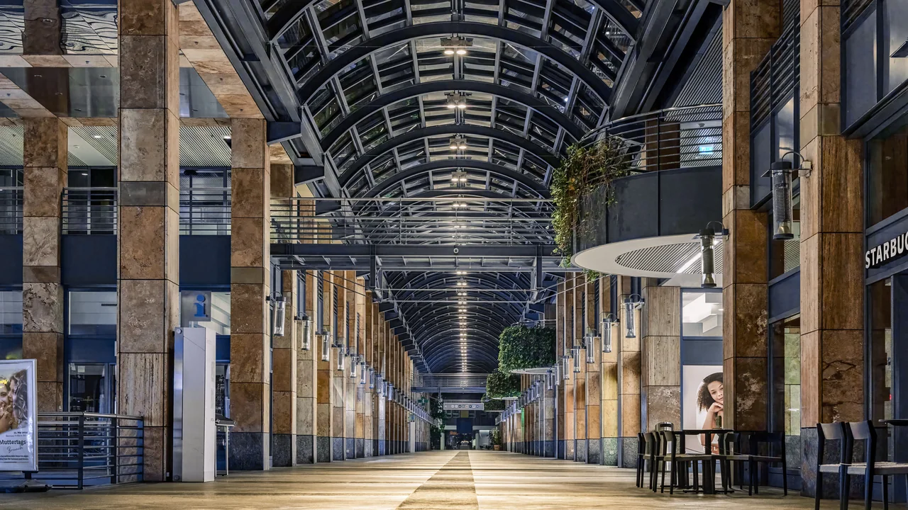 Interior de um shopping center, com lojas e circulação de consumidores