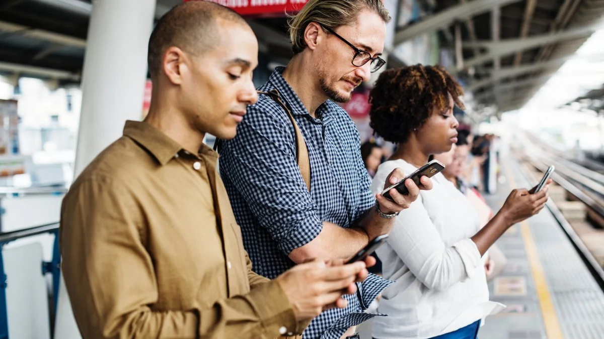 Pessoa consulta informações no smartphone em uma estação ferroviária