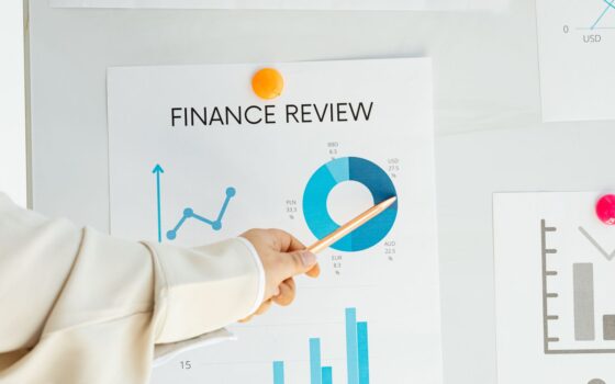 Mão apontando para um relatório financeiro com gráficos e tendências de mercado