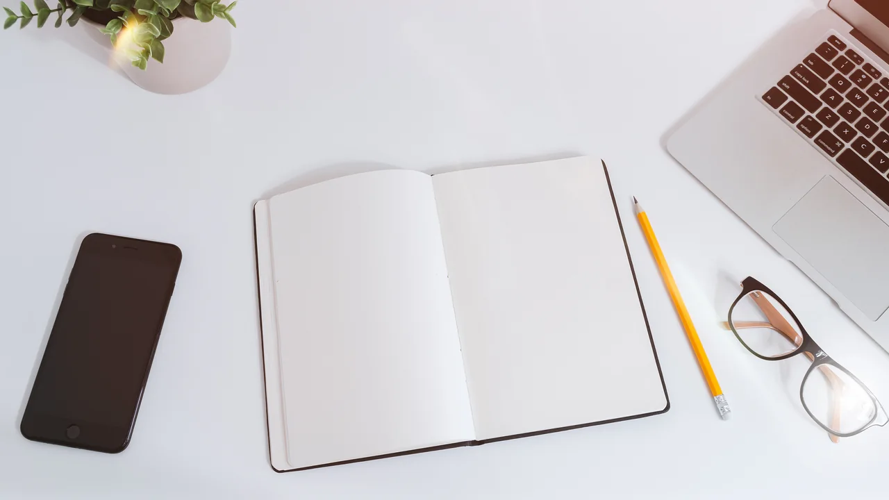 Mesa com celular, notebook e anotações para consulta financeira
