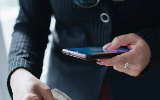 Mulher segurando celular e dinheiro em um escritório