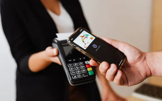Pessoa aproxima o celular de uma máquina para fazer um pagamento digital