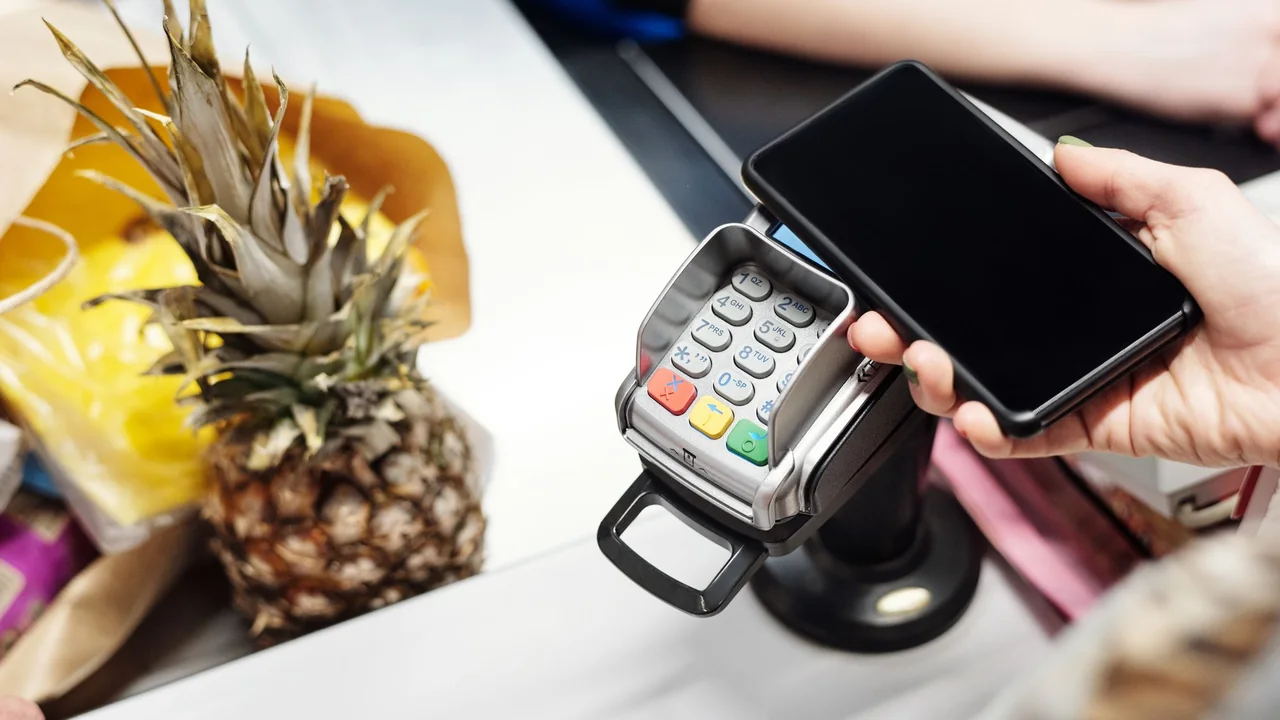 Cliente usa o celular para pagar uma compra em uma máquina de cartão