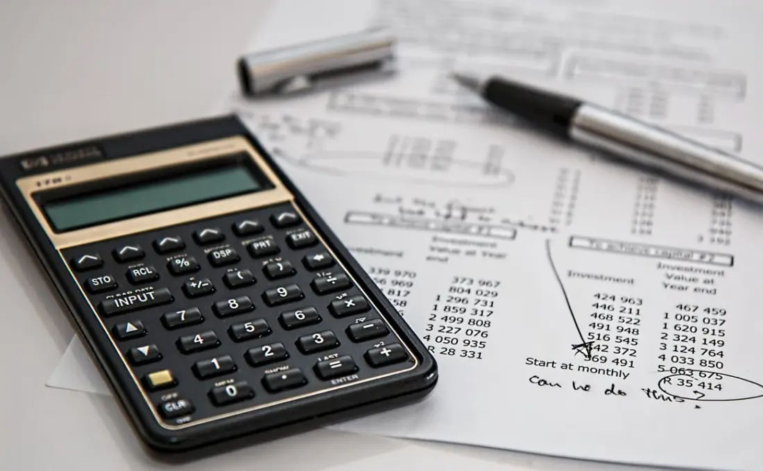 Calculadora sobre documentos financeiros em uma mesa, usada para ilustrar a conferência de tributos