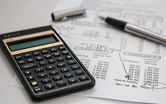 Calculadora sobre documentos financeiros em uma mesa, usada para ilustrar a conferência de tributos
