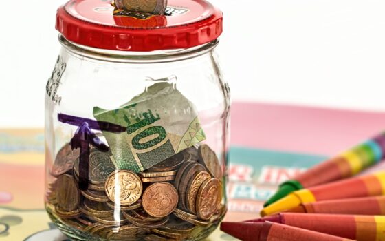 Cofrinho rosa cercado por moedas, representando a formação de uma reserva financeira