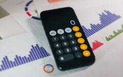 Pessoa usa a calculadora no celular sobre documentos financeiros