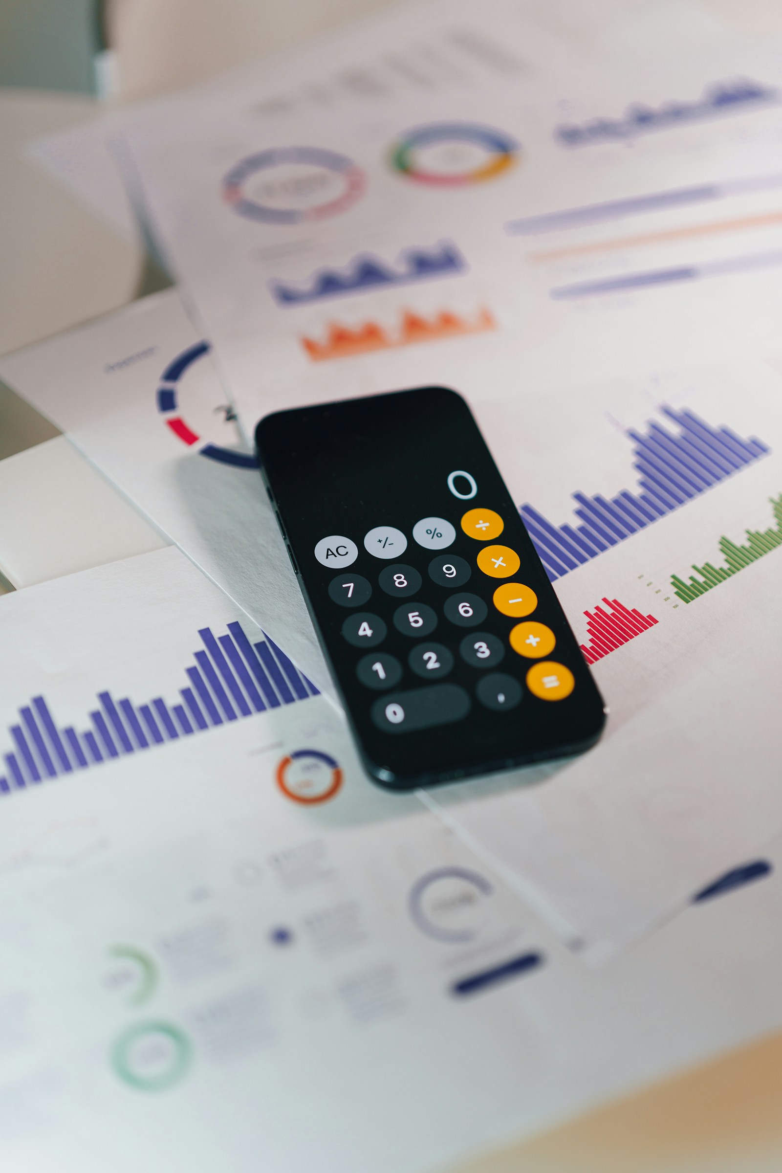 Pessoa usa a calculadora no celular sobre documentos financeiros