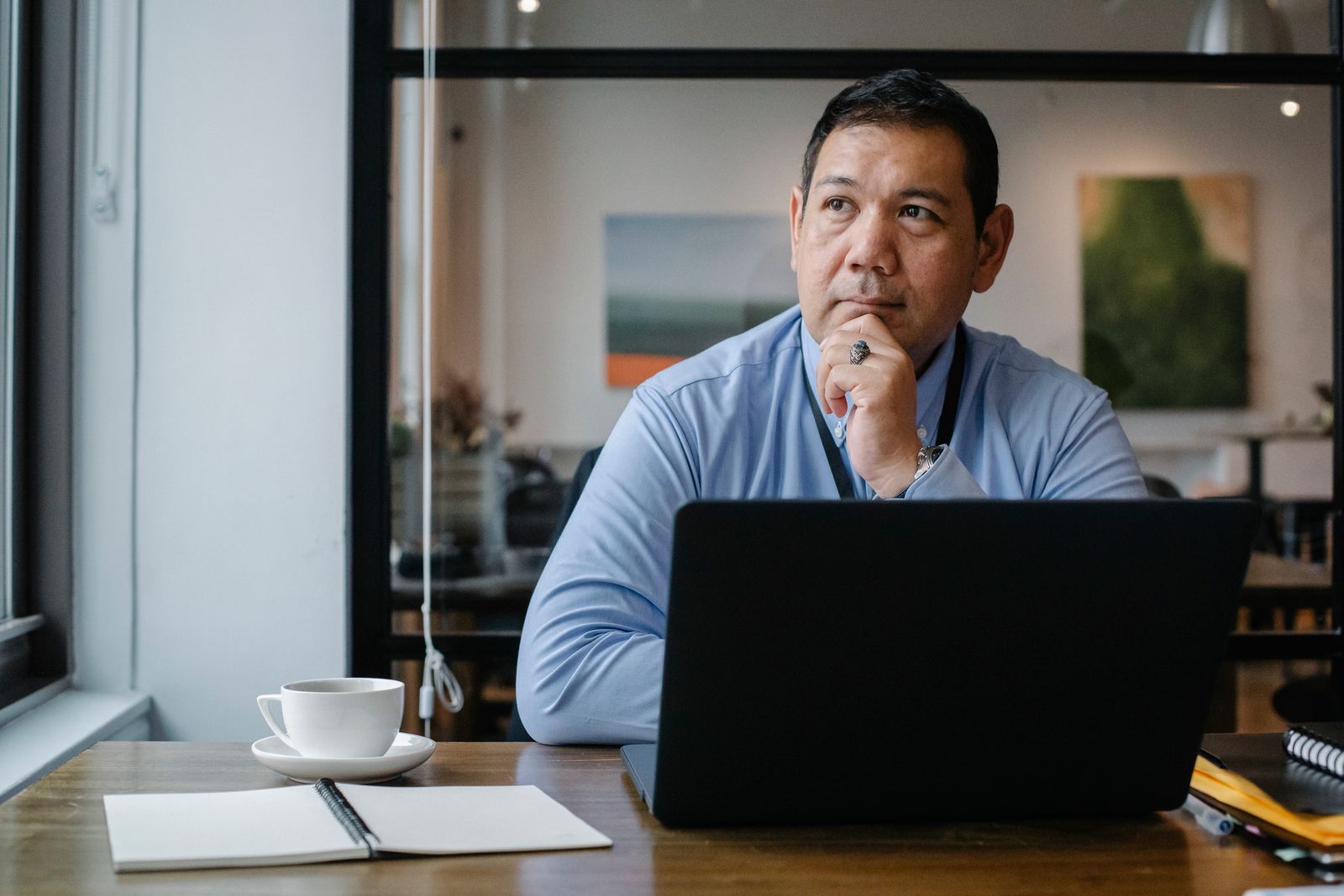Homem sentado em um escritório usa um notebook e observa a tela com expressão concentrada