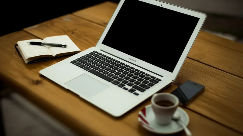 Mesa com celular, laptop e café, representando decisões sobre juros e dinheiro
