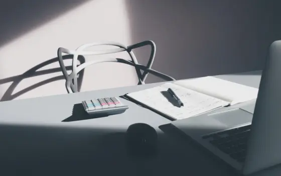 Mesa com laptop, calculadora e documentos, representando a análise de juros e investimentos