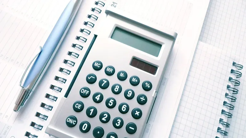 Calculadora, caneta e calendário sobre uma mesa de trabalho