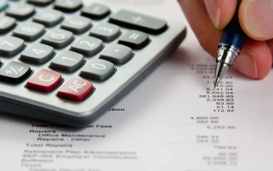 Calculadora e caneta sobre planilha de valores