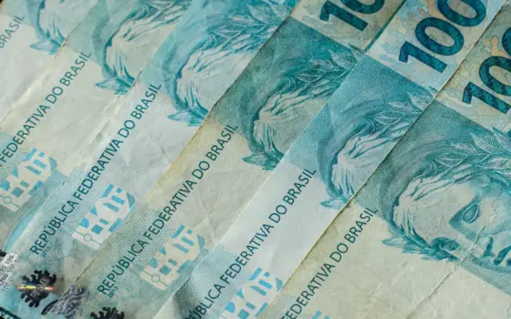 Cédulas de real sobre uma superfície, em imagem de contexto para investimentos do Tesouro Direto