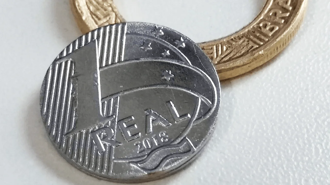 Moeda de um real sobre fundo claro, usada para ilustrar investimentos de pequeno valor