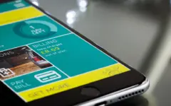 Pessoa consulta um aplicativo de banco no celular para verificar dinheiro a receber