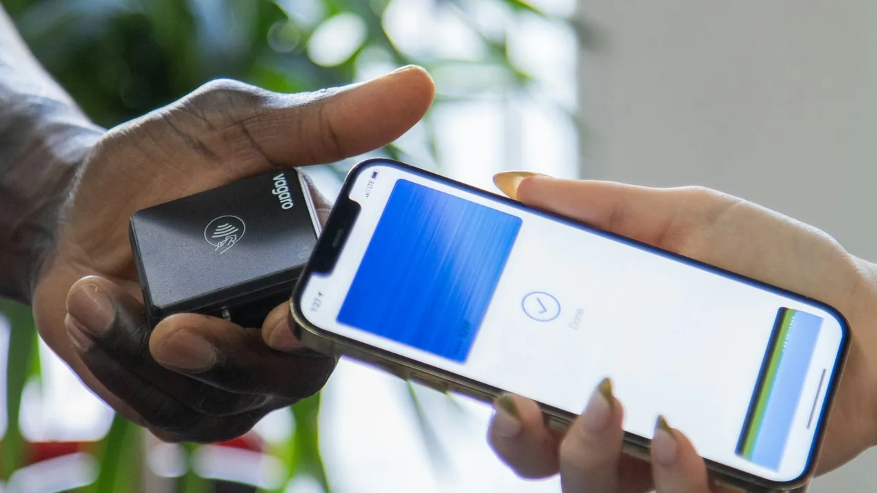 Pessoa usando celular próximo a uma maquininha de pagamento