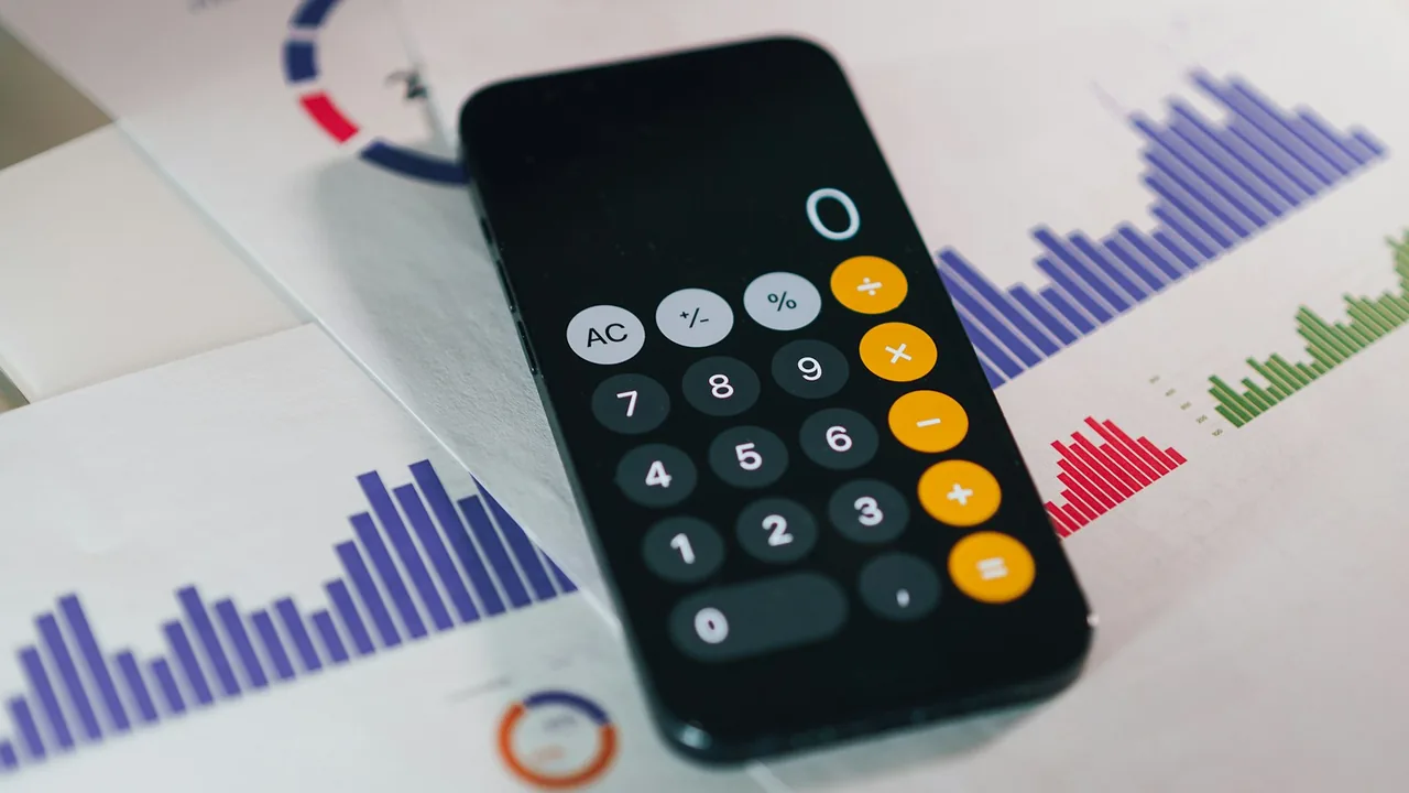 Celular com calculadora sobre gráficos financeiros