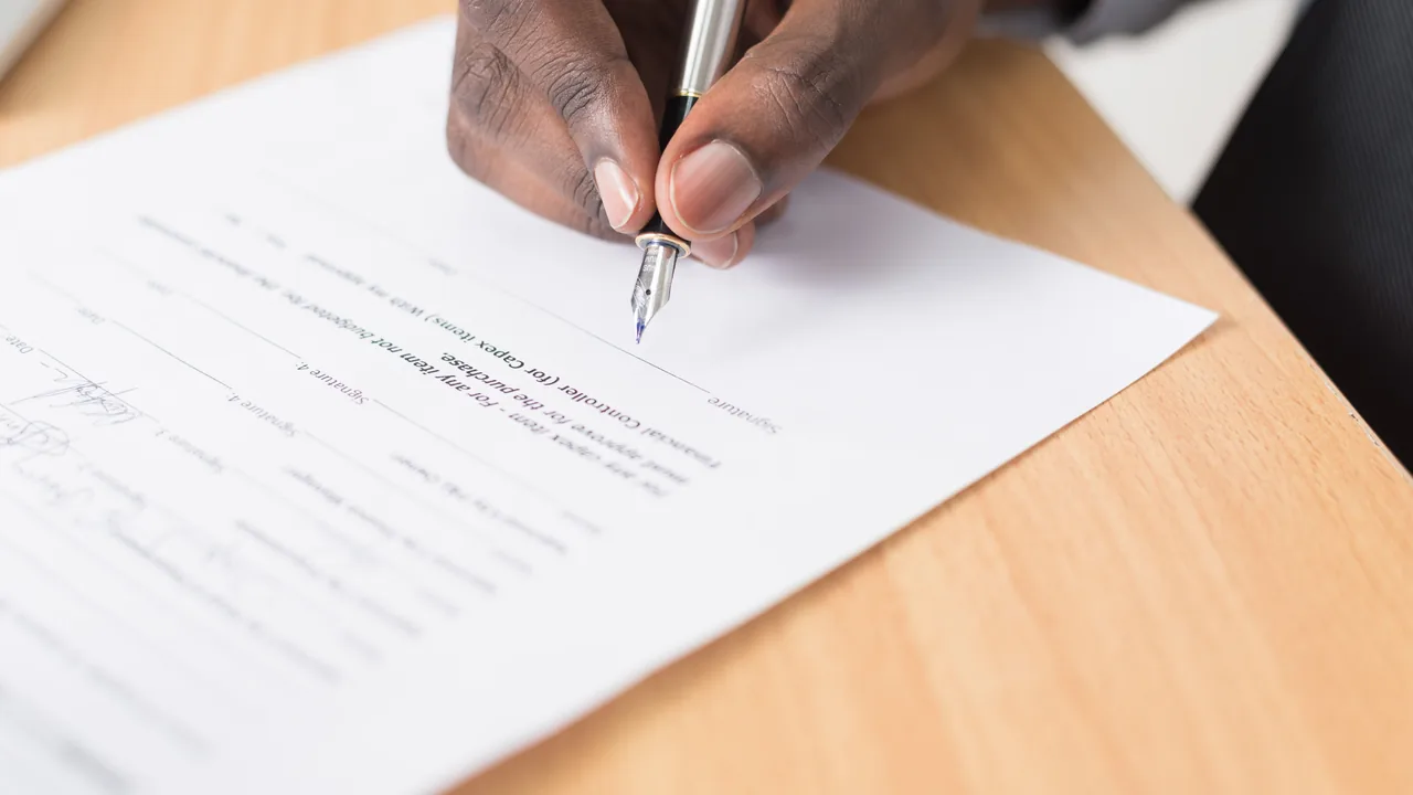 Pessoa assinando contrato de crédito sobre uma mesa