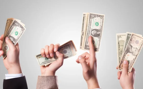 Imagem destacada: mãos segurando cédulas, usada para representar dinheiro e investimento.