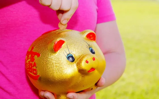 investimento para crianças: criança guardando dinheiro em cofrinho