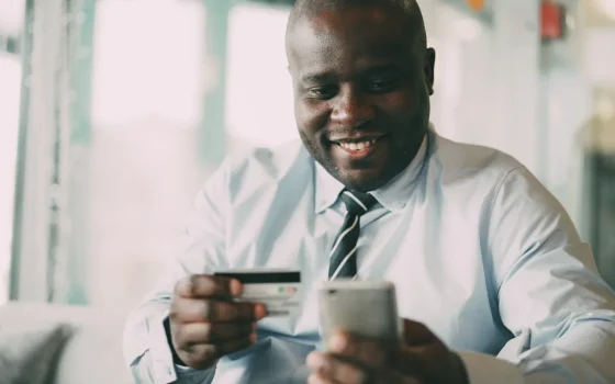 Pessoa usando smartphone e cartão para pagamento