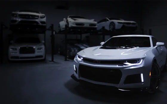 Carro branco em uma garagem com outros veículos