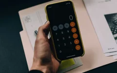 Pessoa usando calculadora no celular sobre documentos e contas