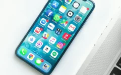 Celular sobre uma mesa ao lado de um laptop