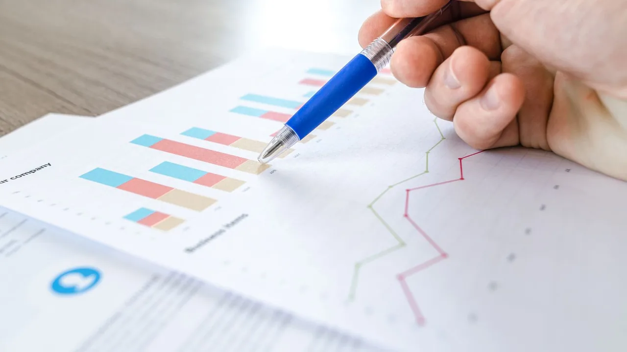 Pessoa analisando gráficos financeiros em um documento, imagem ilustrativa sobre planejamento para regularizar dívida.