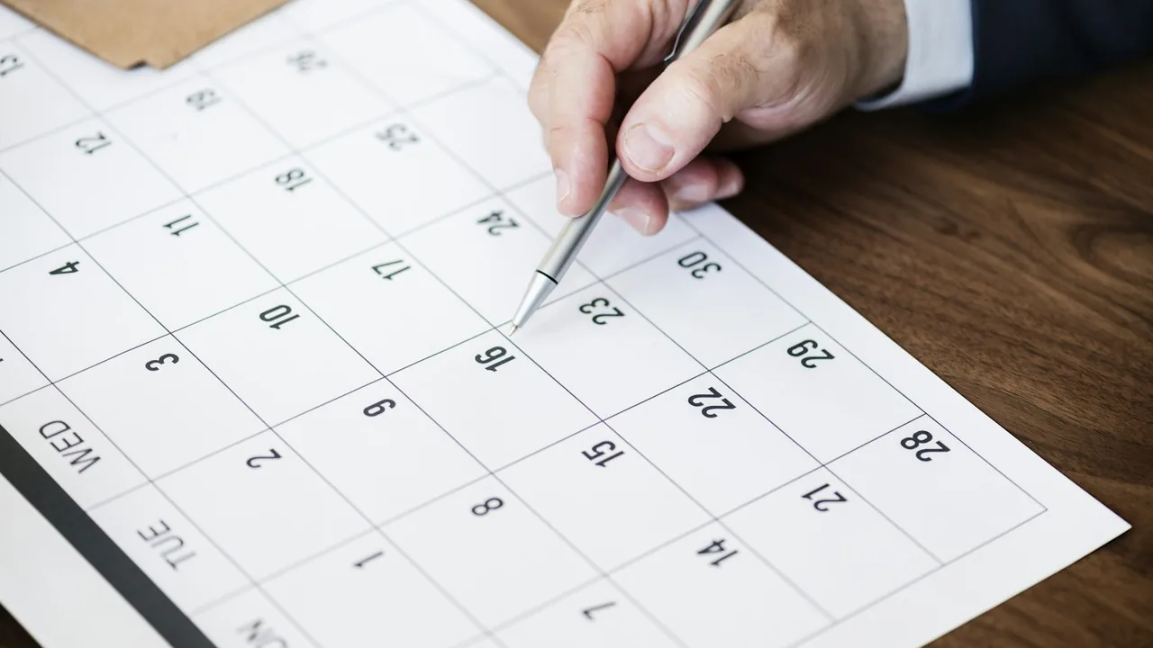 Mão marcando um dia em um calendário de trabalho