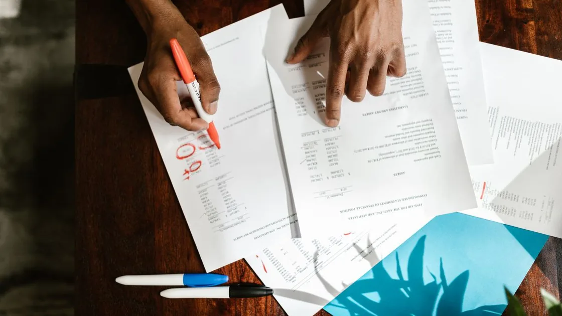 Pessoa analisando documentos de um contrato sobre uma mesa