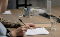 Pessoa assinando documentos de um contrato em uma mesa