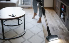 Pessoa aspira o chão de uma sala de estar em uma casa