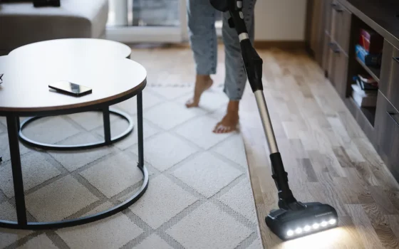 Pessoa aspira o chão de uma sala de estar em uma casa