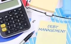Calculadora, óculos e anotações sobre gestão de dívidas