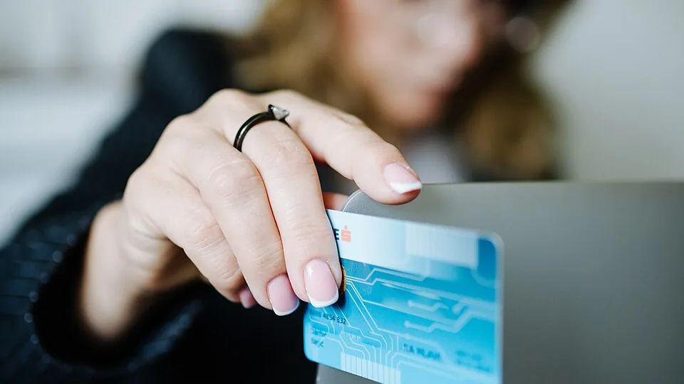 Pessoa usando cartão em compra online no laptop